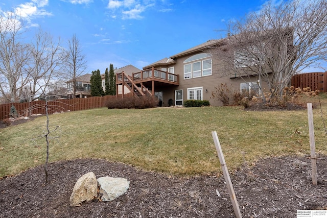 rear view of house featuring a fenced backyard, a lawn, a wooden deck, and stairs