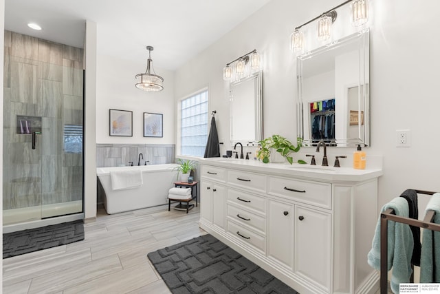 bathroom featuring a freestanding tub, a sink, tile walls, double vanity, and a stall shower