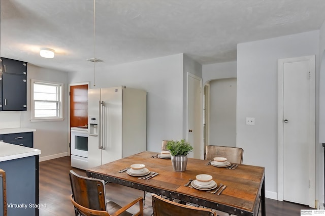 dining area with baseboards, visible vents, arched walkways, and dark wood-type flooring