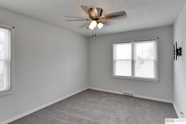 carpeted spare room with visible vents, ceiling fan, a textured ceiling, and baseboards