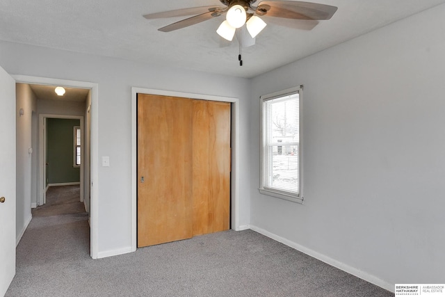 unfurnished bedroom featuring a closet, carpet, a ceiling fan, and baseboards