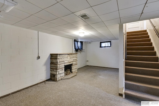 basement featuring concrete block wall, visible vents, stairway, and a stone fireplace