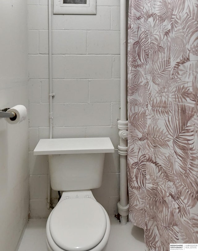 bathroom with concrete block wall and toilet