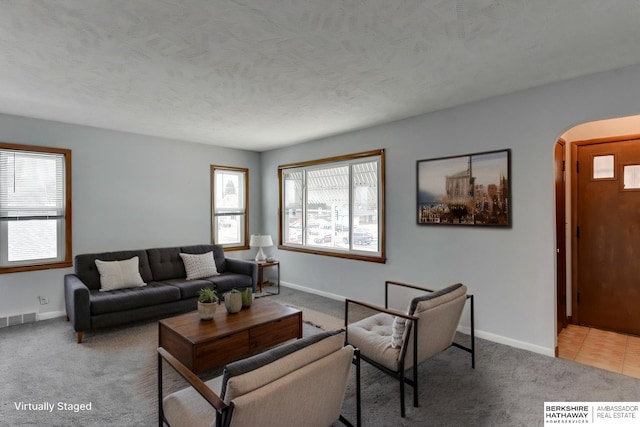 living room featuring baseboards, visible vents, arched walkways, and carpet flooring