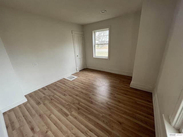 spare room with visible vents, baseboards, and wood finished floors