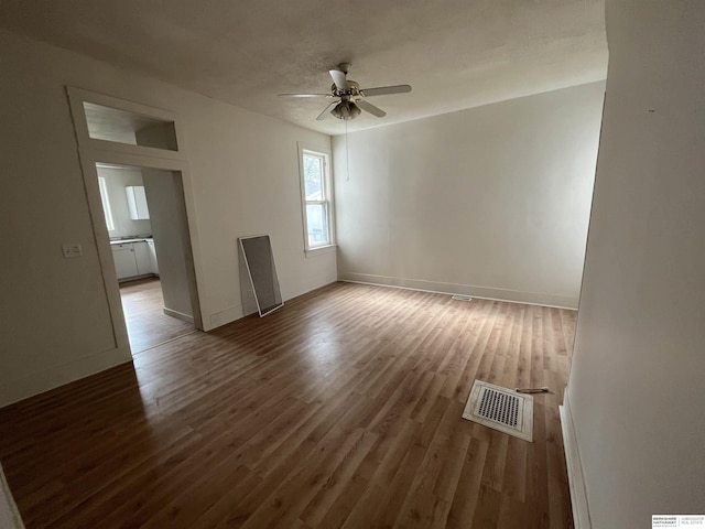 spare room featuring visible vents, ceiling fan, baseboards, and wood finished floors