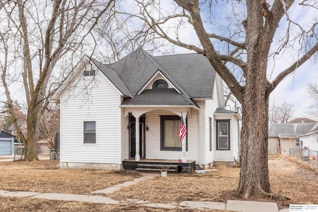 view of front of house featuring covered porch, roof with shingles, and fence