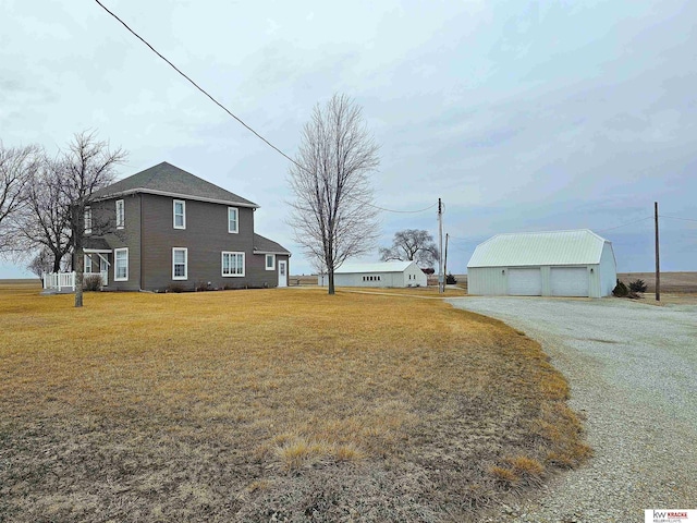 exterior space with a detached garage, a yard, and an outbuilding