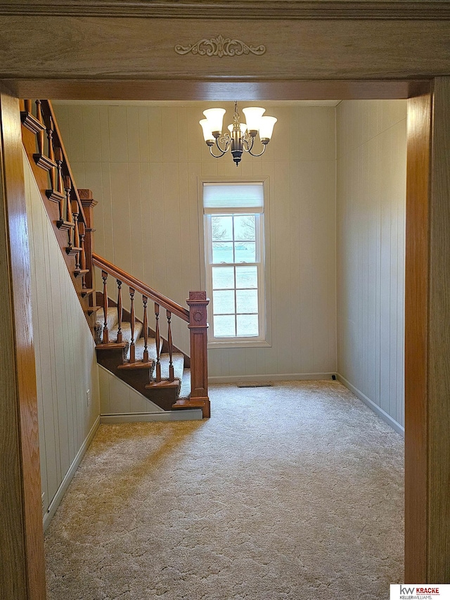 interior space with an inviting chandelier, carpet, and baseboards