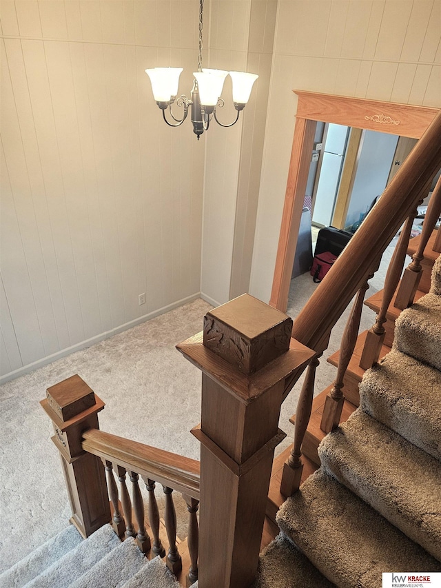 staircase with a notable chandelier and carpet