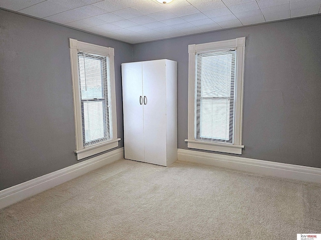 unfurnished room with carpet and baseboards