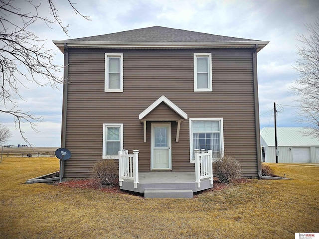 rear view of house featuring a yard and a shingled roof