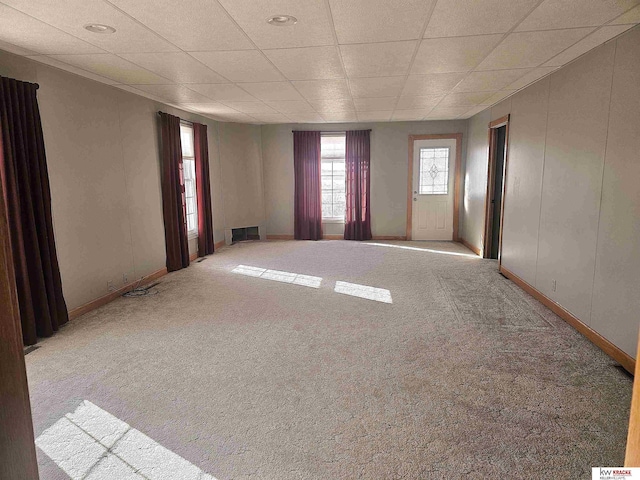 empty room with a drop ceiling, visible vents, and carpet floors