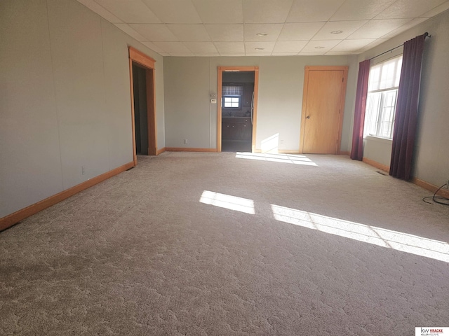 carpeted empty room featuring baseboards and a paneled ceiling