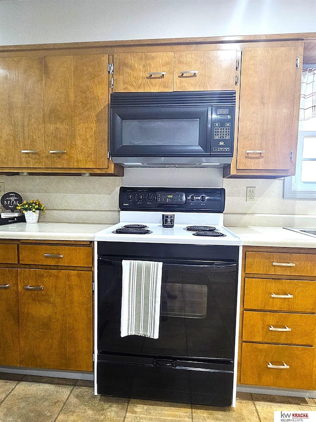 kitchen featuring tasteful backsplash, electric range oven, brown cabinetry, light countertops, and black microwave