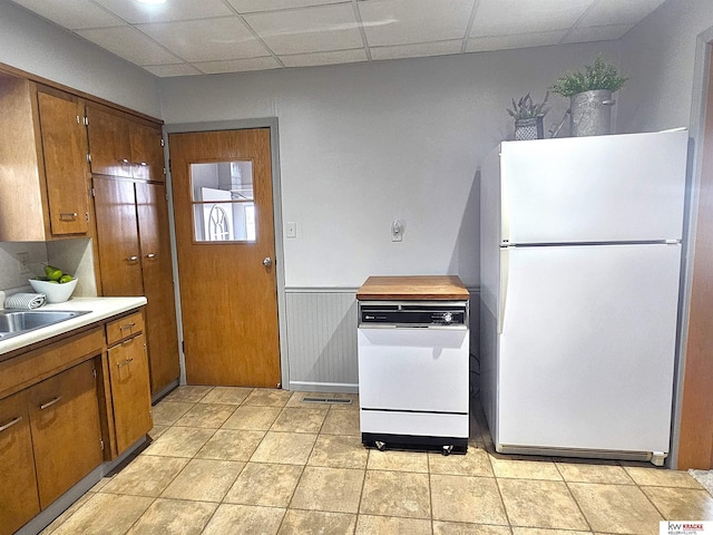 kitchen featuring a drop ceiling, white appliances, brown cabinets, and light countertops