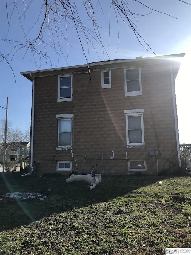 rear view of property with brick siding and a yard