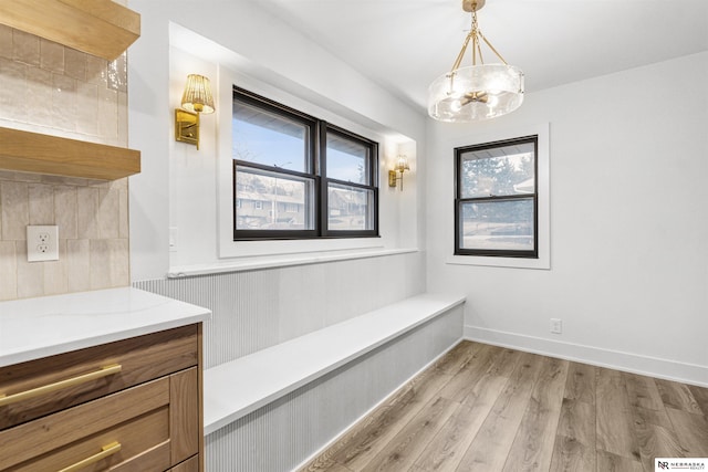 unfurnished dining area featuring light wood finished floors, baseboards, and an inviting chandelier