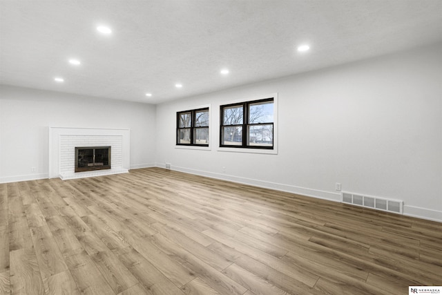 unfurnished living room featuring light wood-style flooring, recessed lighting, a fireplace, visible vents, and baseboards