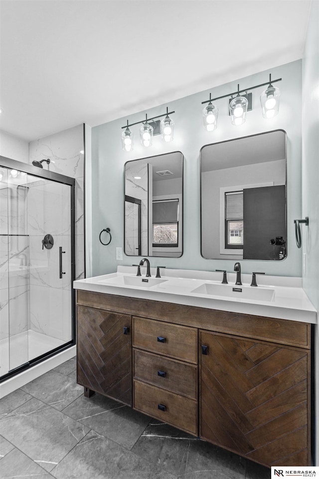 full bathroom with double vanity, marble finish floor, a marble finish shower, and a sink