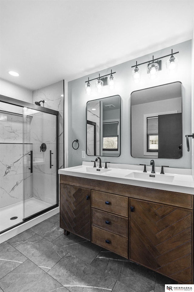 full bath with marble finish floor, a sink, a marble finish shower, and double vanity