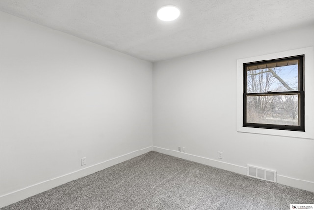 carpeted empty room with visible vents, a textured ceiling, and baseboards