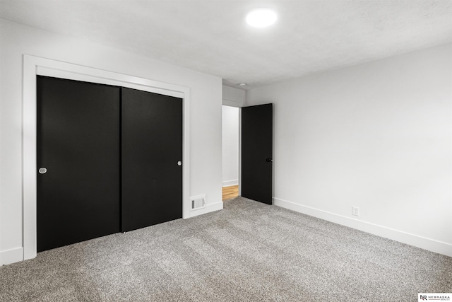 unfurnished bedroom featuring baseboards, a closet, visible vents, and carpet flooring