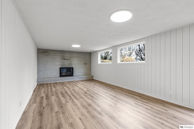 unfurnished living room featuring light wood-style floors, baseboards, and a glass covered fireplace