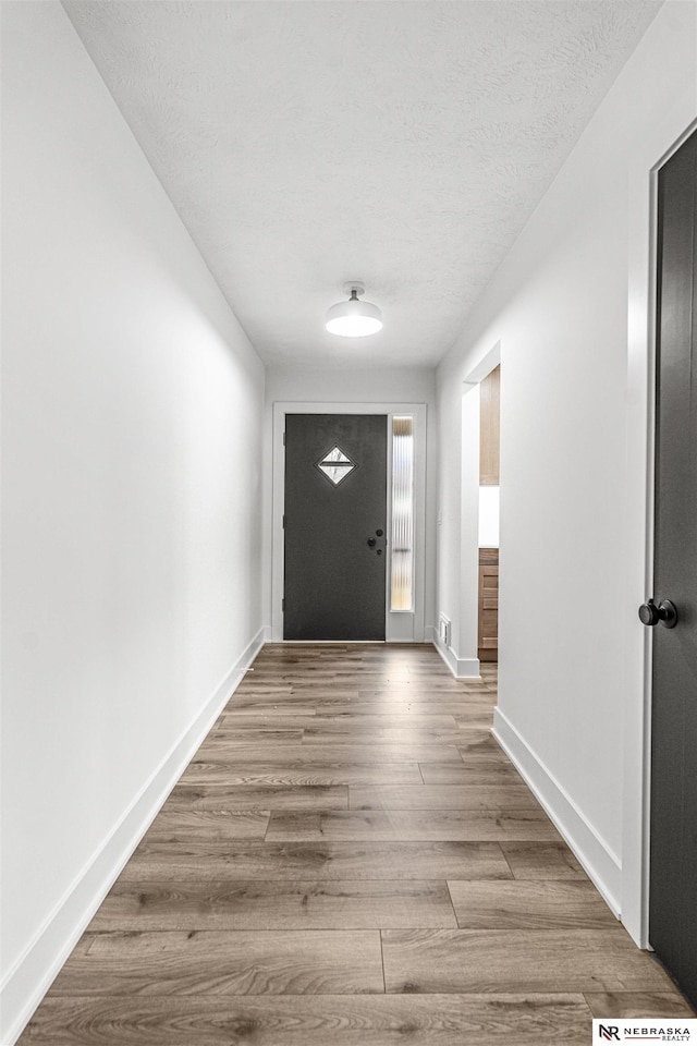 entryway featuring a textured ceiling, baseboards, and wood finished floors