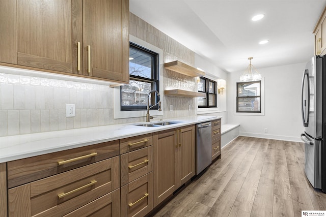 kitchen featuring light wood finished floors, tasteful backsplash, light countertops, appliances with stainless steel finishes, and a sink