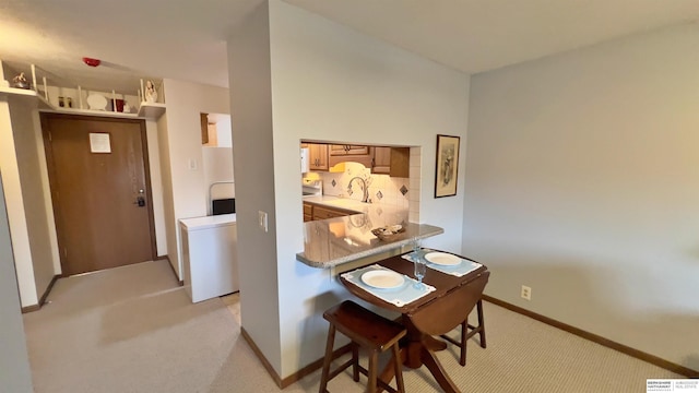 dining room with baseboards and light colored carpet