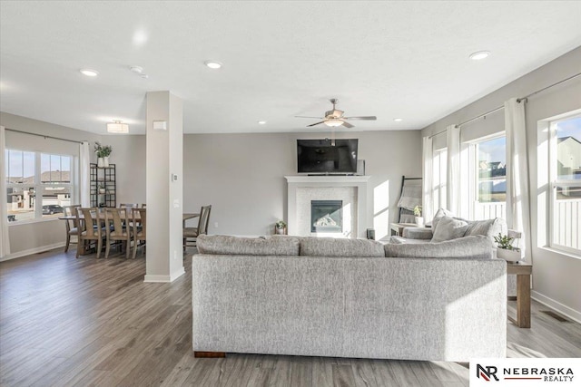 living room with a glass covered fireplace, recessed lighting, wood finished floors, and baseboards