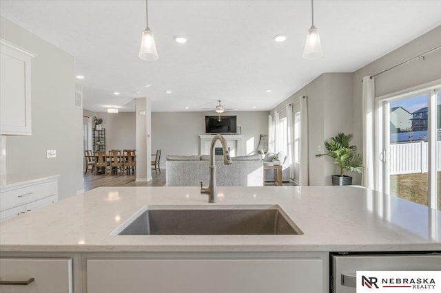 kitchen featuring a fireplace, open floor plan, a sink, and decorative light fixtures