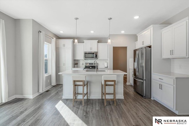 kitchen with appliances with stainless steel finishes, light countertops, white cabinetry, and wood finished floors