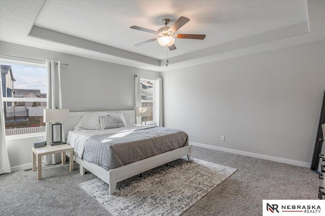 bedroom featuring a tray ceiling, carpet flooring, and baseboards