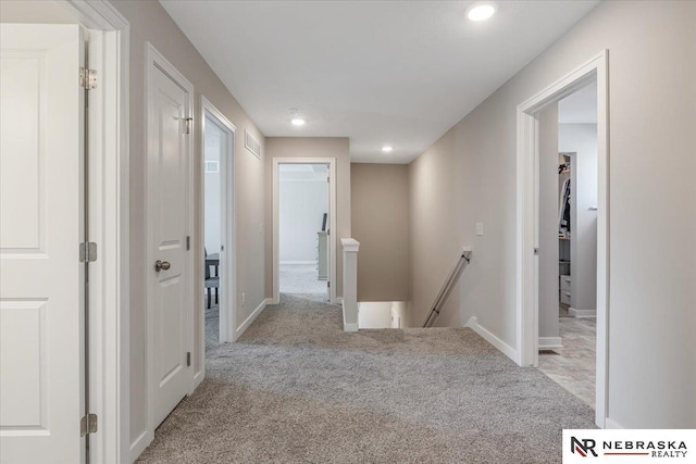 hallway with recessed lighting, carpet floors, visible vents, baseboards, and an upstairs landing