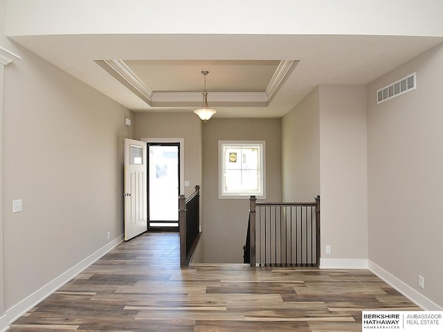 entryway featuring a tray ceiling, wood finished floors, visible vents, and baseboards