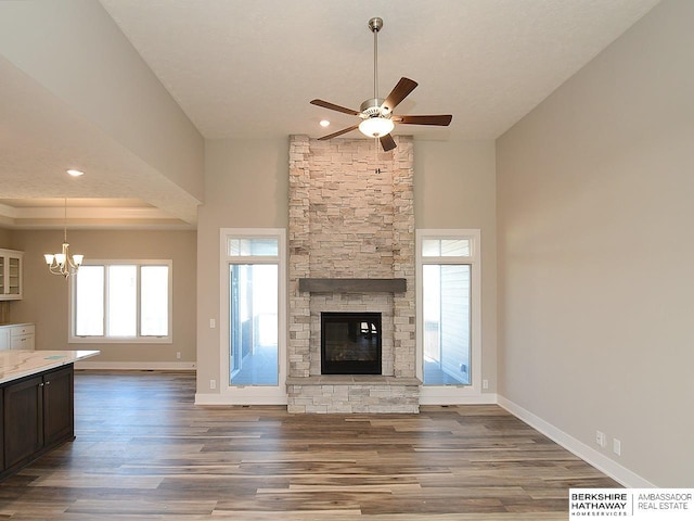 unfurnished living room featuring a tray ceiling, a fireplace, baseboards, and wood finished floors