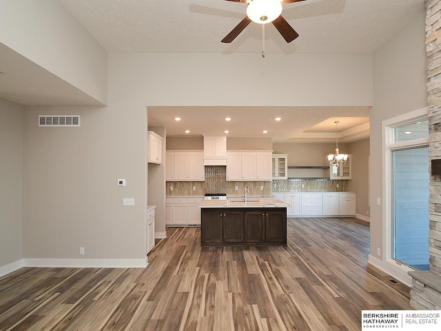 kitchen featuring dark wood-style flooring, a sink, visible vents, light countertops, and tasteful backsplash