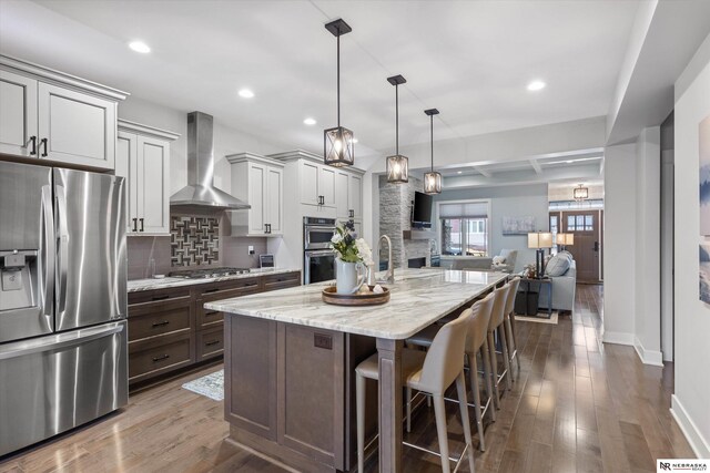 6919 Wildrye Rd, Lincoln, NE 68521 - kitchen featuring stainless steel appliances, wall chimney range hood, dark wood-style flooring, and backsplash