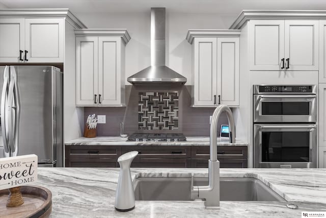 6919 Wildrye Rd, Lincoln, NE 68521 - kitchen featuring appliances with stainless steel finishes, wall chimney range hood, decorative backsplash, and light stone countertops