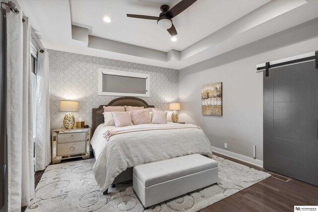 6919 Wildrye Rd, Lincoln, NE 68521 - bedroom featuring a barn door, wood finished floors, baseboards, a raised ceiling, and wallpapered walls