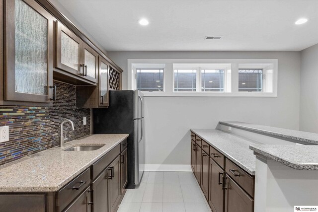 6919 Wildrye Rd, Lincoln, NE 68521 - kitchen featuring a sink, visible vents, baseboards, dark brown cabinets, and tasteful backsplash