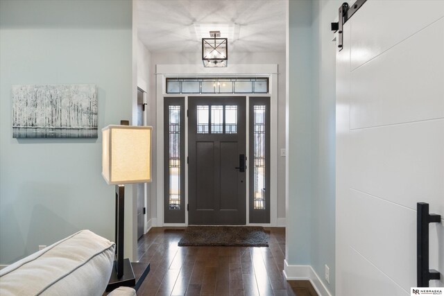 6919 Wildrye Rd, Lincoln, NE 68521 - entrance foyer with a barn door, dark wood-style flooring, and baseboards