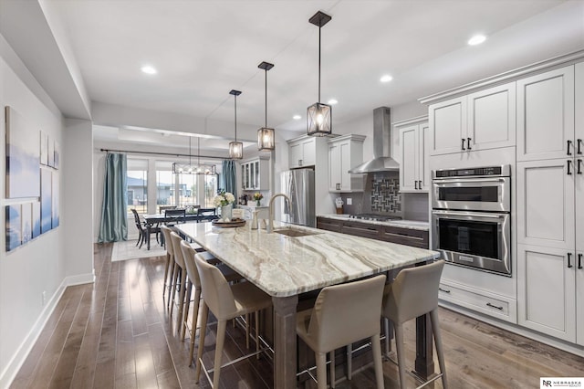 6919 Wildrye Rd, Lincoln, NE 68521 - kitchen featuring tasteful backsplash, appliances with stainless steel finishes, a kitchen breakfast bar, wall chimney range hood, and a sink