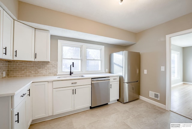 kitchen featuring stainless steel appliances, visible vents, backsplash, white cabinetry, and a sink