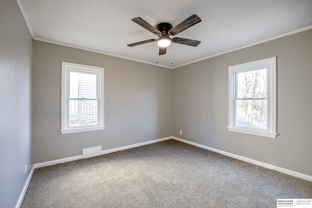 empty room featuring baseboards, carpet, visible vents, and crown molding