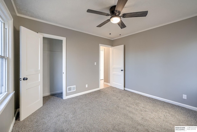 unfurnished bedroom with carpet floors, baseboards, visible vents, and ornamental molding