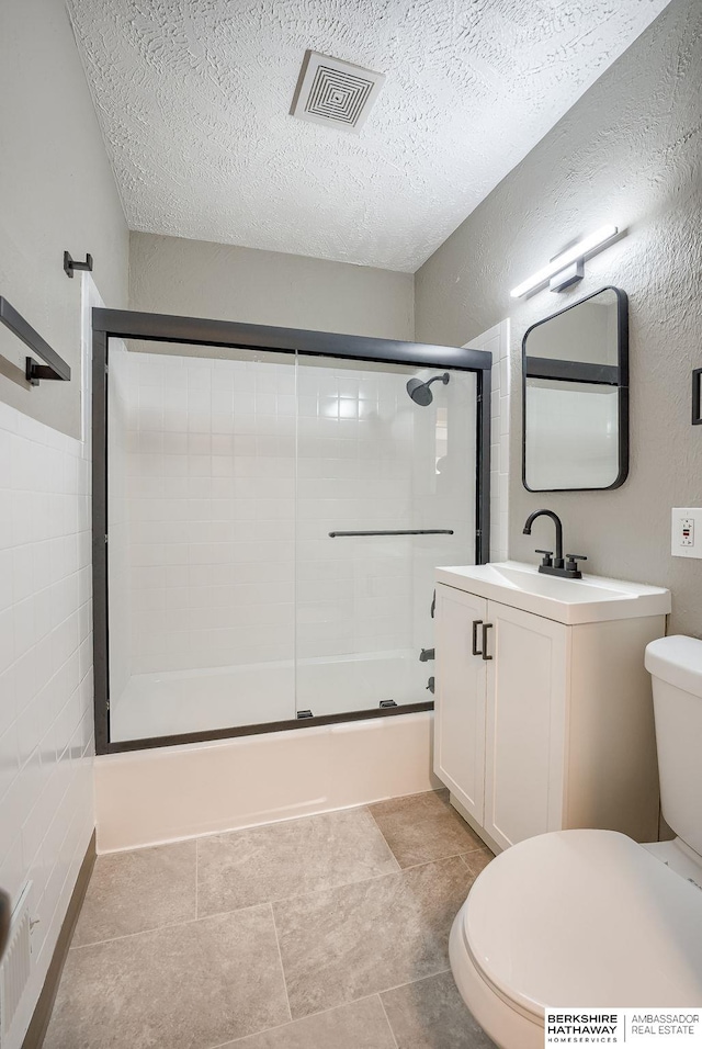 bathroom featuring visible vents, toilet, shower / bath combination with glass door, a textured ceiling, and vanity