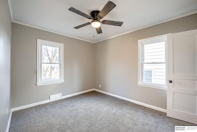 carpeted spare room with ornamental molding, visible vents, baseboards, and a ceiling fan